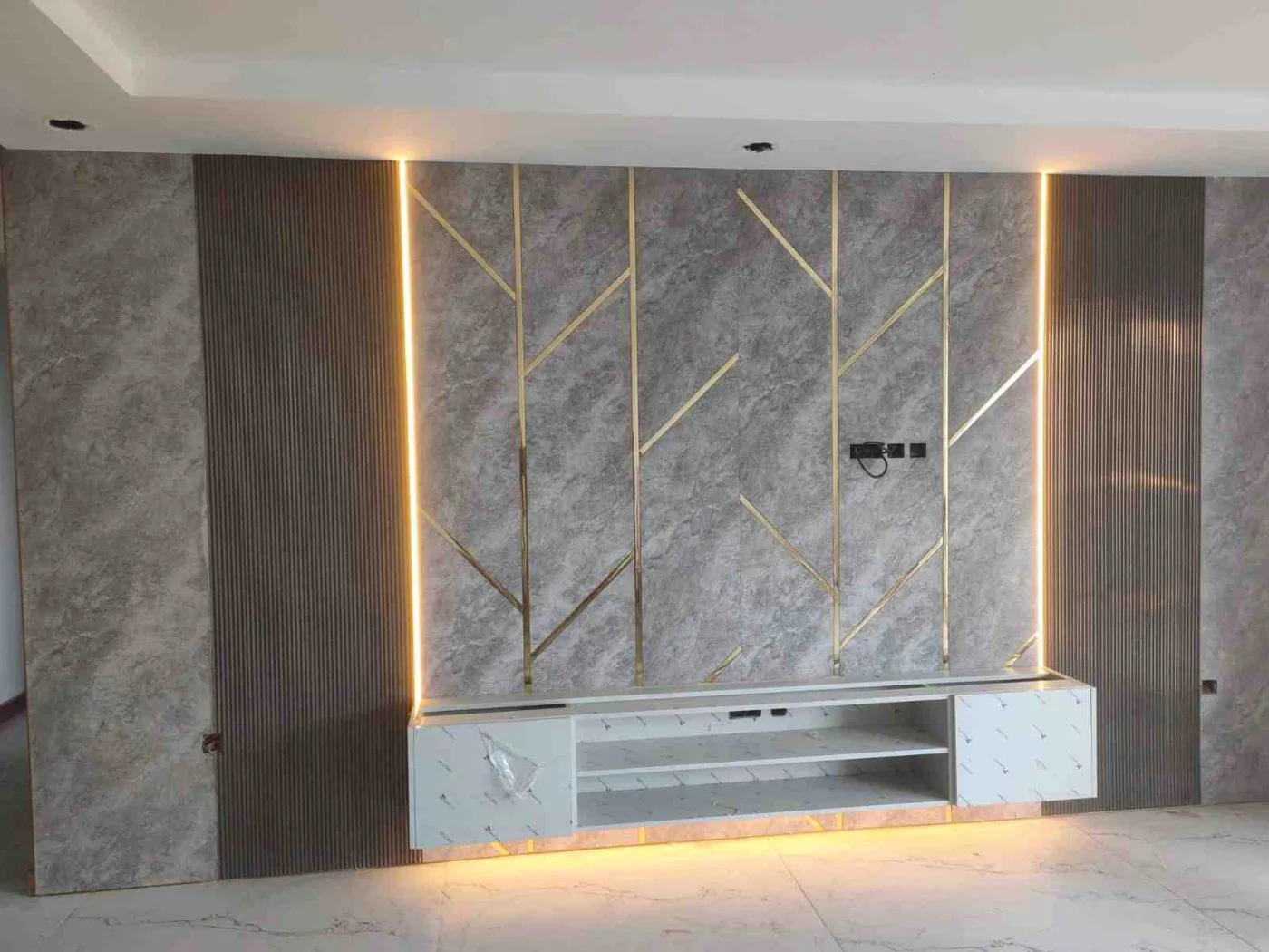 After: finished TV wall with marble-effect panels, gold accents and LED lighting