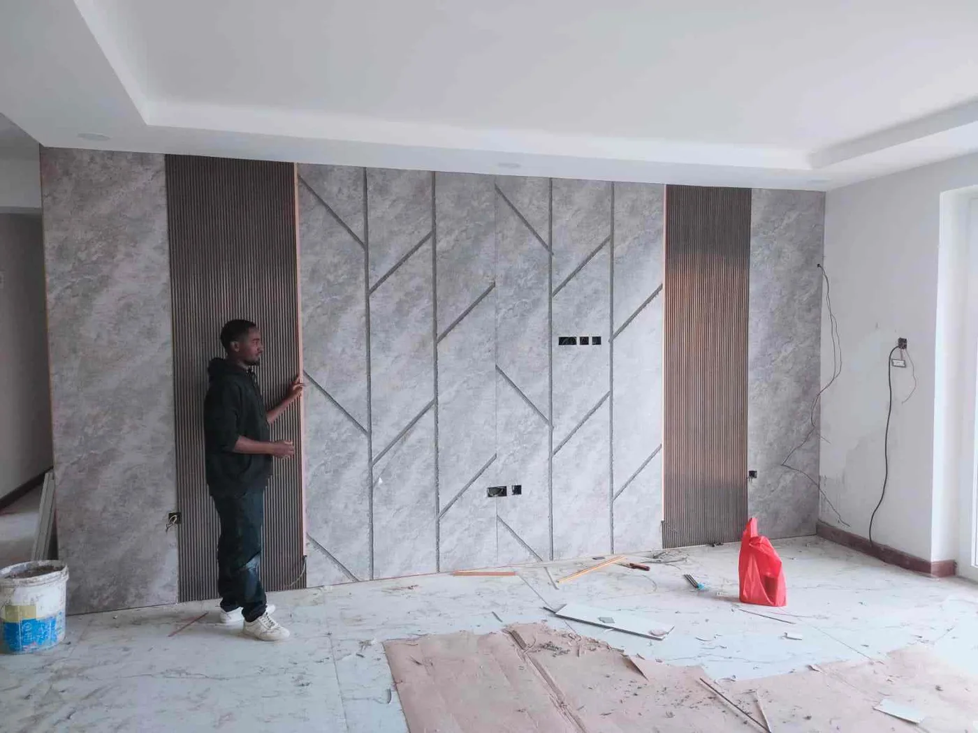 Before: installer fixing grey stone-effect wall panels and gold trims
