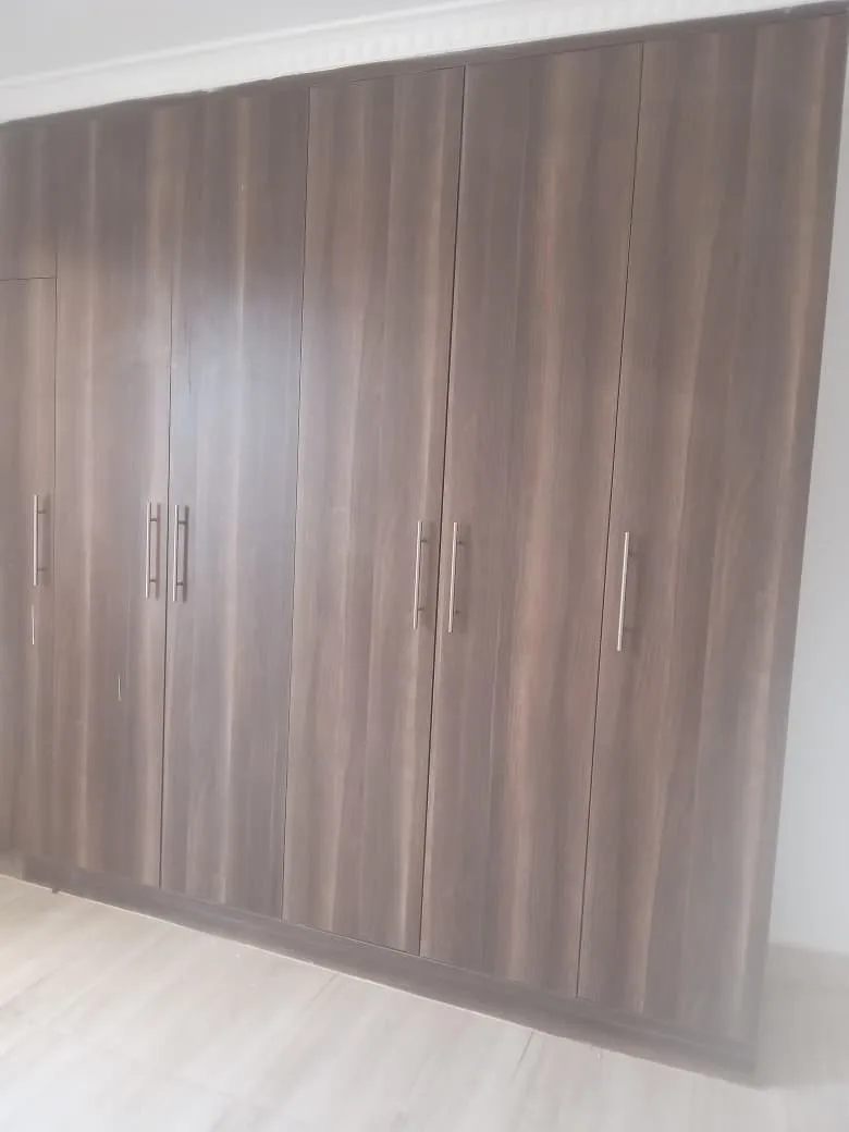 Wood-grain fitted wardrobe, doors closed, wide view