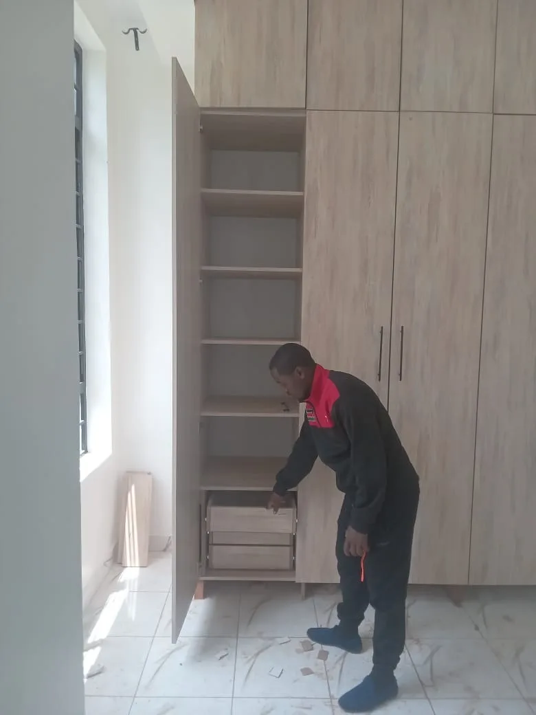 Carpenter fitting wardrobe shelves and drawers on site